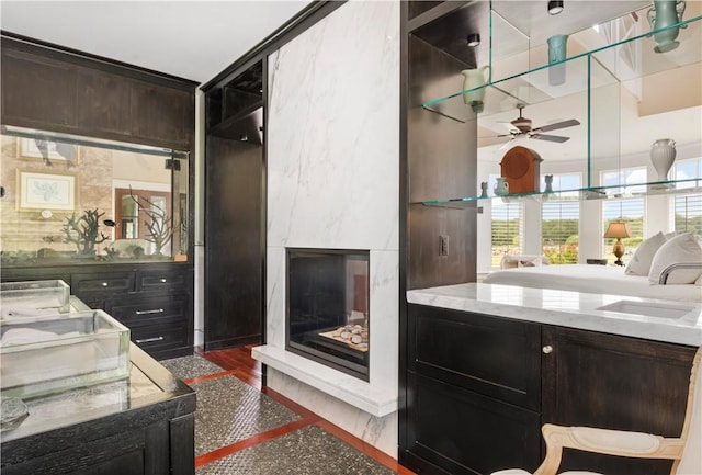 bathroom with a ceiling fan, a sink, a premium fireplace, and wood finished floors