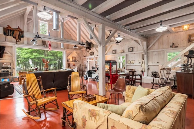 living area featuring a wealth of natural light, lofted ceiling with beams, and wood walls