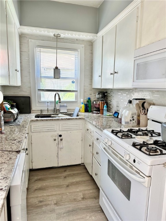 kitchen featuring white cabinets, pendant lighting, white appliances, sink, and light hardwood / wood-style flooring