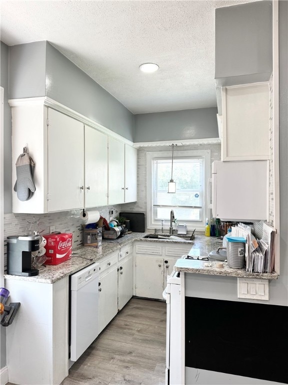 kitchen featuring white cabinets, pendant lighting, backsplash, light wood-type flooring, and dishwasher