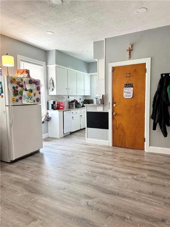 kitchen featuring a textured ceiling, light hardwood / wood-style flooring, white cabinetry, and white appliances