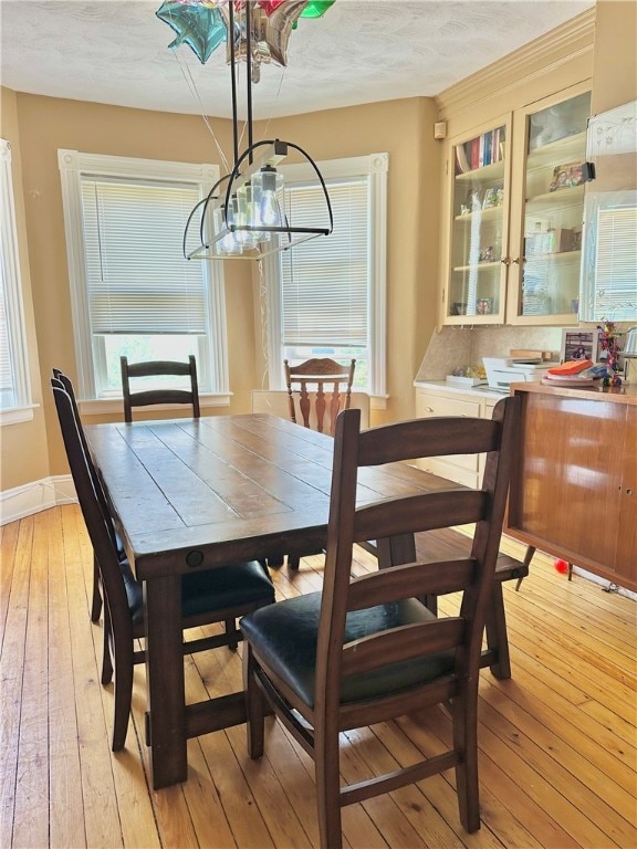 dining area with a healthy amount of sunlight, light hardwood / wood-style floors, and an inviting chandelier