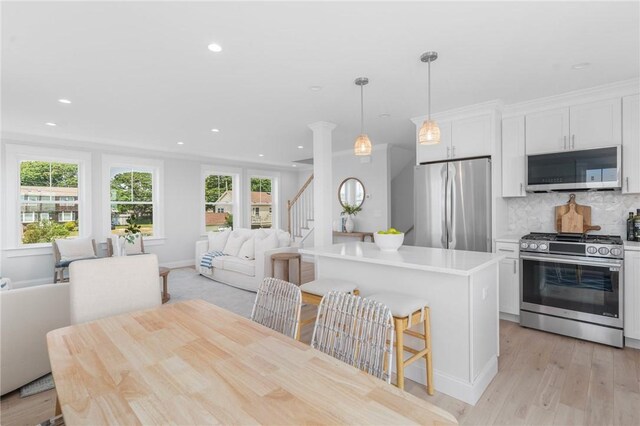 kitchen featuring decorative light fixtures, stainless steel appliances, white cabinetry, and a healthy amount of sunlight