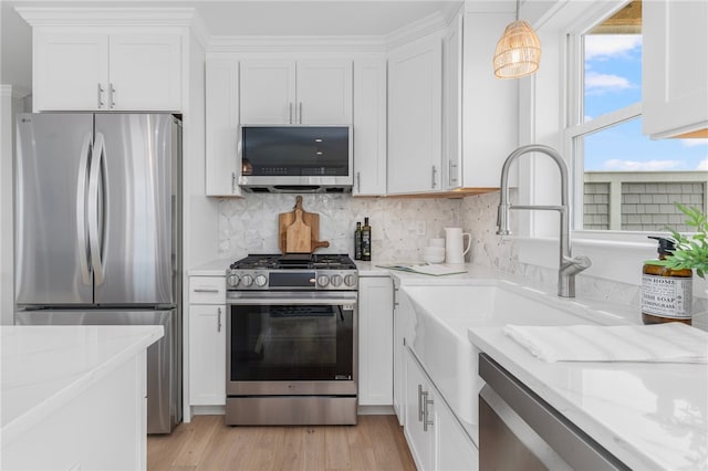 kitchen with pendant lighting, tasteful backsplash, light hardwood / wood-style floors, stainless steel appliances, and white cabinetry