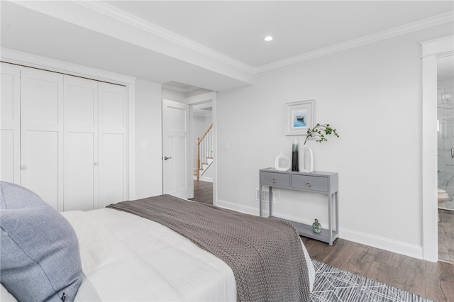 bedroom featuring dark wood-type flooring, a closet, connected bathroom, and crown molding