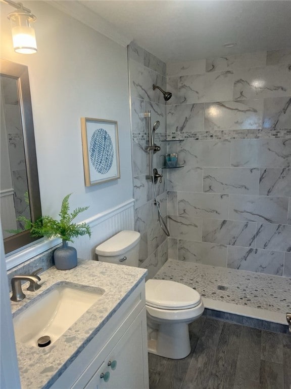 bathroom with vanity, toilet, wood-type flooring, and a tile shower