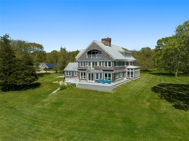 rear view of property featuring a lawn and a wooden deck