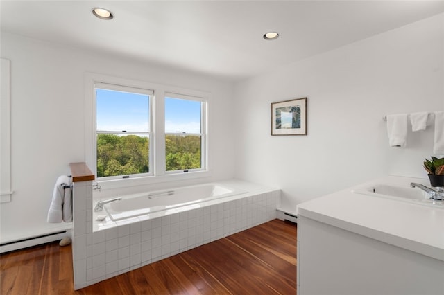 bathroom featuring sink, baseboard heating, wood-type flooring, and a tub