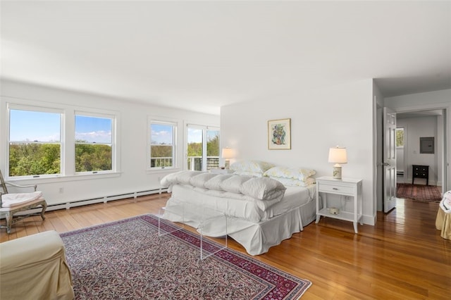 bedroom with baseboard heating and hardwood / wood-style flooring