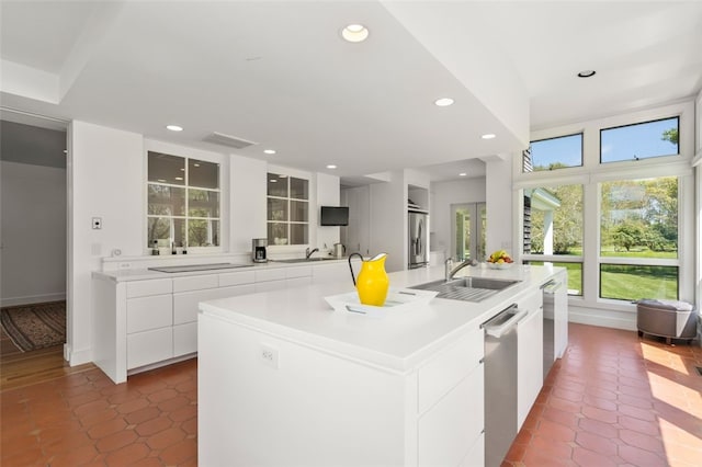 kitchen with sink, white cabinetry, plenty of natural light, and a center island with sink