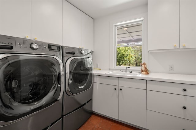 laundry area featuring cabinets, washing machine and clothes dryer, dark tile patterned flooring, and sink