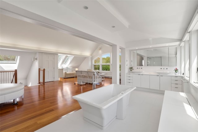 interior space with sink, vaulted ceiling with skylight, and hardwood / wood-style flooring