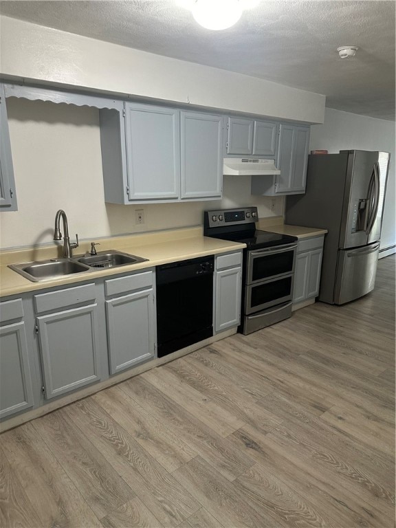 kitchen featuring stainless steel appliances, light hardwood / wood-style floors, sink, and a textured ceiling