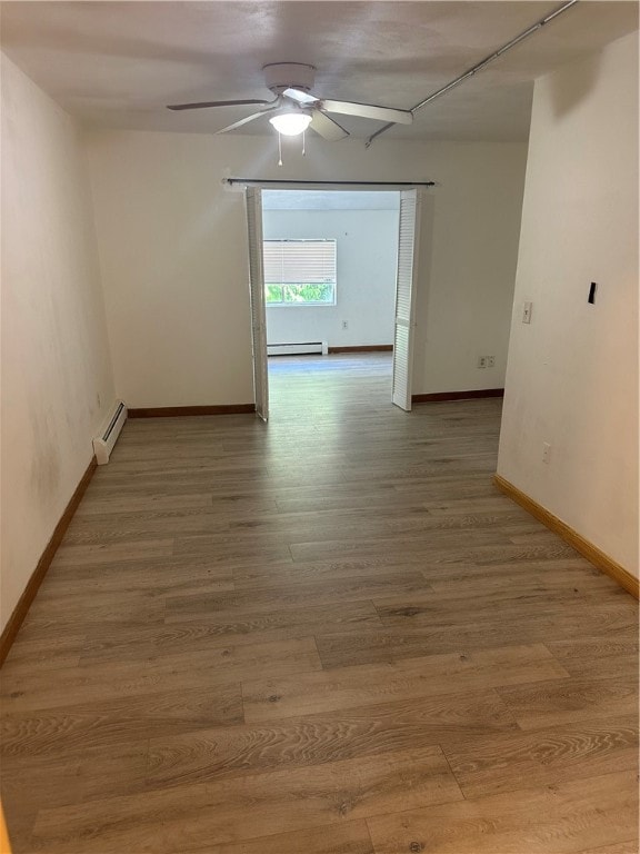 empty room with a baseboard radiator, ceiling fan, and hardwood / wood-style flooring