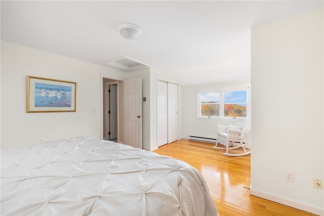 bedroom with light hardwood / wood-style flooring, a closet, and a baseboard radiator