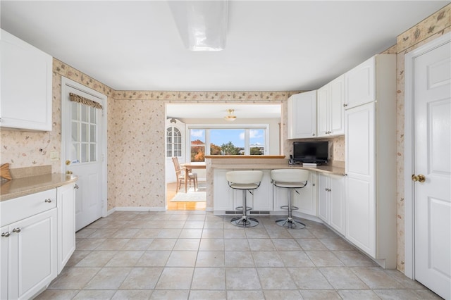 kitchen featuring a kitchen breakfast bar, light tile patterned floors, and white cabinetry