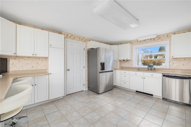 kitchen featuring white cabinets, appliances with stainless steel finishes, backsplash, and sink