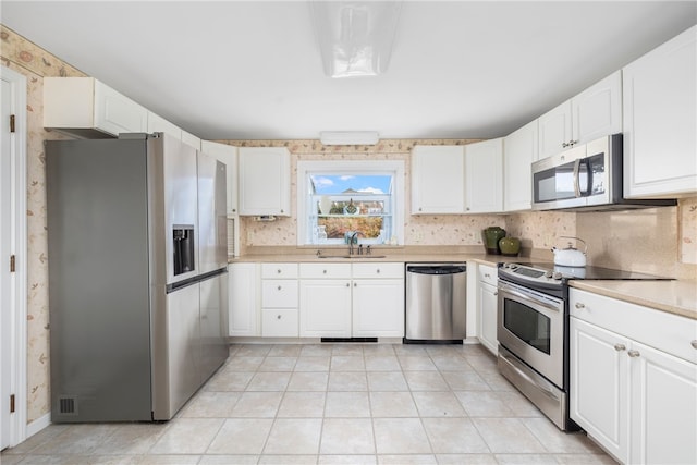 kitchen featuring tasteful backsplash, stainless steel appliances, sink, white cabinets, and light tile patterned flooring