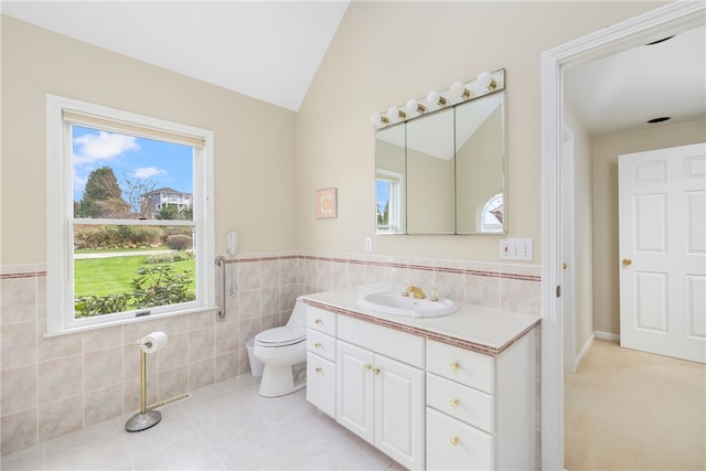 bathroom featuring vanity, toilet, vaulted ceiling, and tile walls