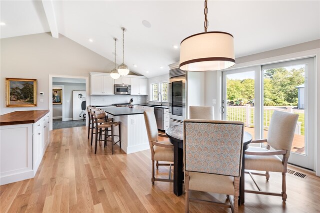 dining space with lofted ceiling with beams, a wealth of natural light, light hardwood / wood-style floors, and sink