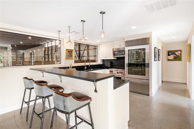 kitchen featuring decorative backsplash, white cabinets, high end appliances, decorative light fixtures, and sink