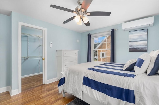 bedroom featuring a wall mounted AC, ceiling fan, a closet, and light hardwood / wood-style flooring