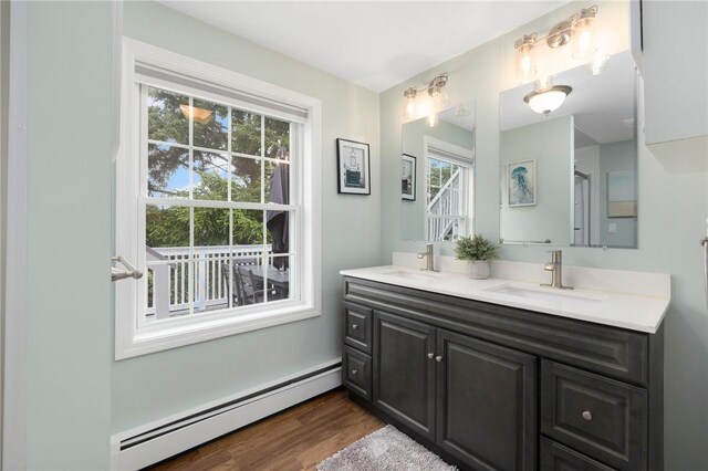 bathroom with hardwood / wood-style floors, plenty of natural light, baseboard heating, and vanity