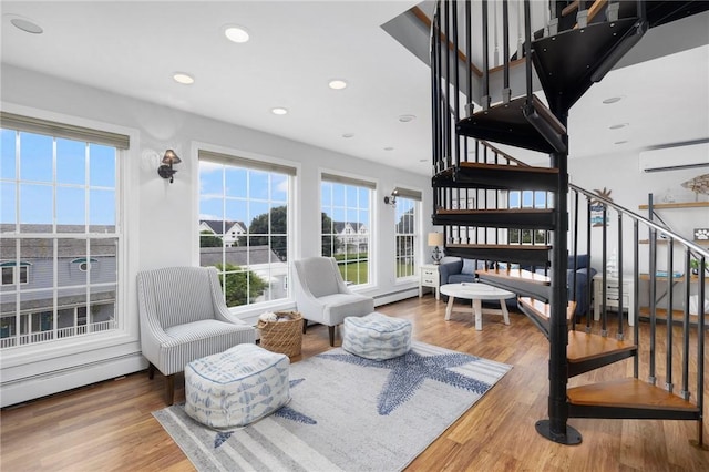 interior space featuring a wall mounted AC, wood-type flooring, and baseboard heating