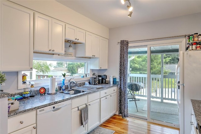 kitchen featuring sink, white appliances, white cabinetry, and dark stone countertops