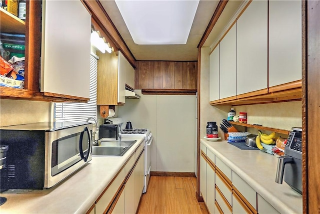 kitchen with sink, white gas stove, white cabinetry, and light hardwood / wood-style flooring