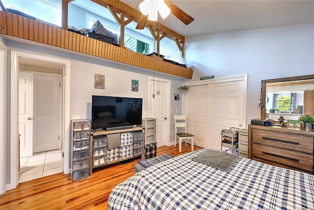 bedroom with ceiling fan, a closet, a towering ceiling, and hardwood / wood-style flooring