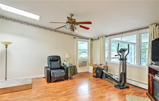 workout room with ceiling fan, a healthy amount of sunlight, light wood-type flooring, and a baseboard radiator