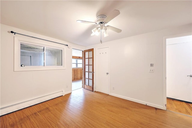 empty room featuring a baseboard heating unit, ceiling fan, and light hardwood / wood-style floors