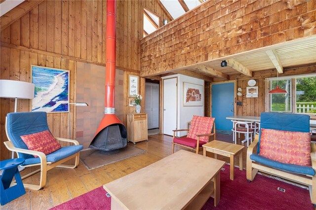 681 Corn Neck Rd, Block Island, RI 02807 - living area with a wood stove, wooden walls, a towering ceiling, wood-type flooring, and beamed ceiling