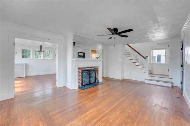 unfurnished living room featuring a brick fireplace, crown molding, ceiling fan, and hardwood / wood-style floors