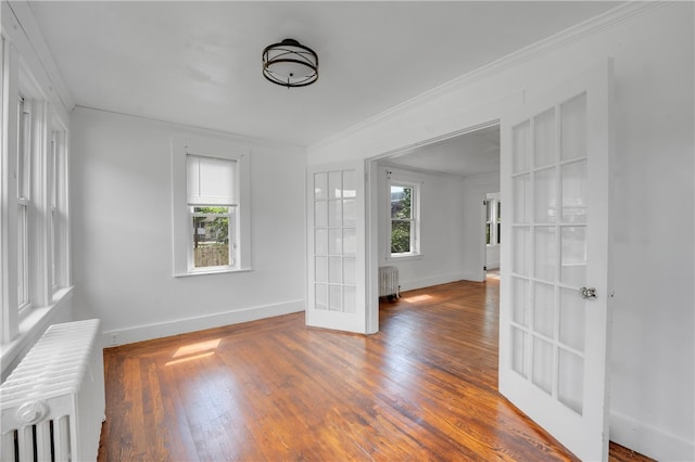 unfurnished room featuring wood-type flooring, french doors, radiator, and crown molding