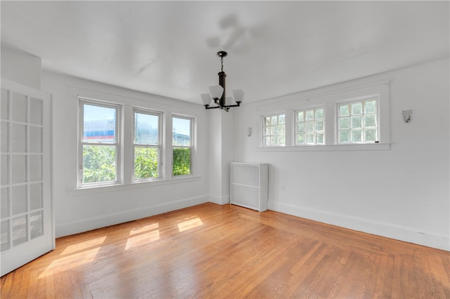 spare room with light hardwood / wood-style flooring and a chandelier