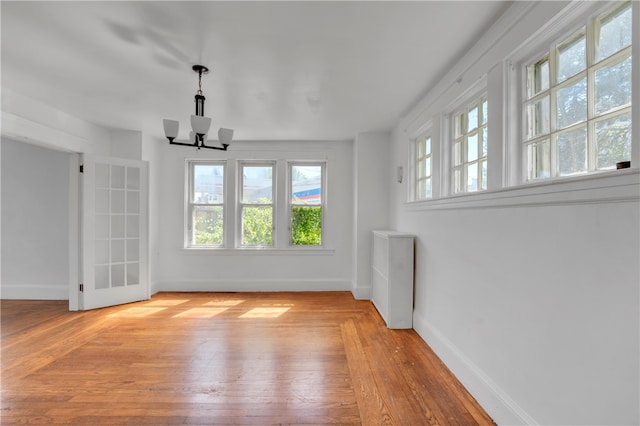 spare room featuring a chandelier and light hardwood / wood-style floors