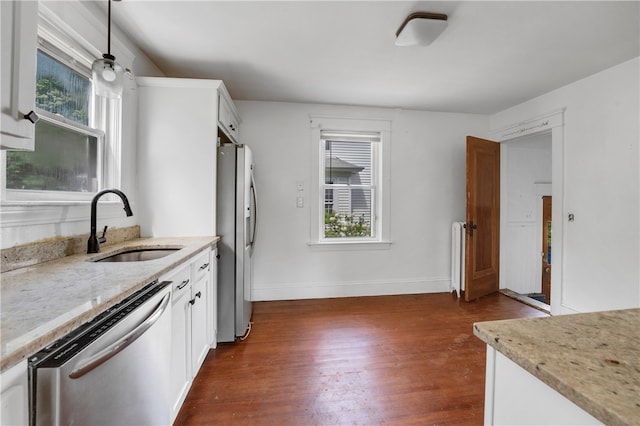 kitchen with stainless steel appliances, pendant lighting, dark hardwood / wood-style floors, white cabinets, and sink