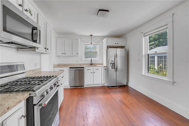 kitchen featuring light stone counters, white cabinetry, hardwood / wood-style flooring, stainless steel appliances, and sink