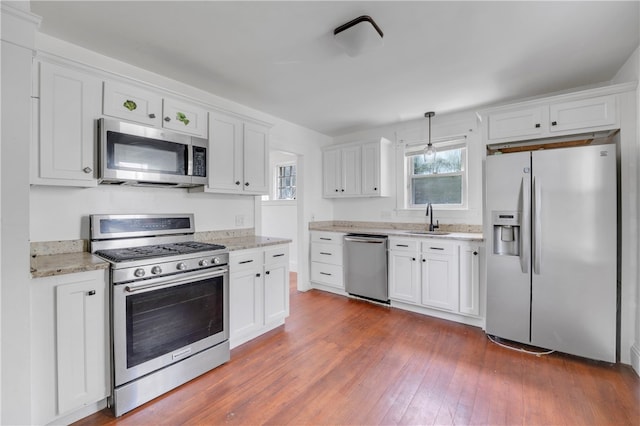 kitchen with appliances with stainless steel finishes, sink, wood-type flooring, and white cabinetry