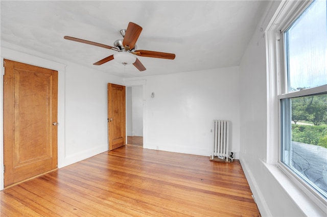 spare room with ceiling fan, light hardwood / wood-style flooring, and radiator