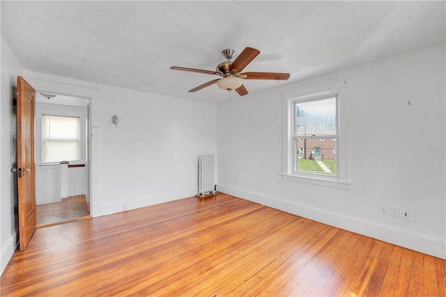 empty room featuring ceiling fan, wood-type flooring, and radiator