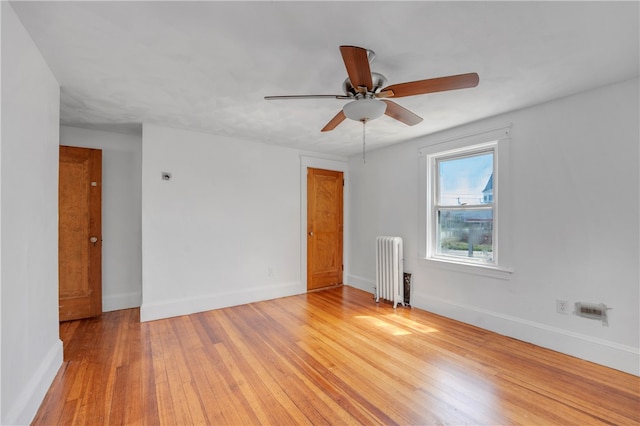 spare room featuring ceiling fan, radiator, and hardwood / wood-style flooring