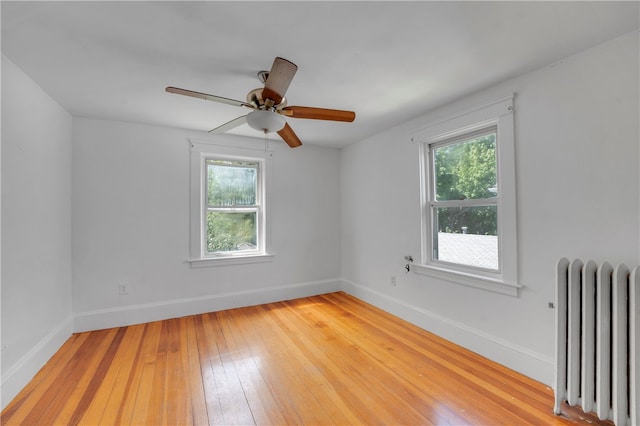 empty room featuring light wood-type flooring, a wealth of natural light, and radiator