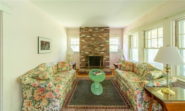 living room with hardwood / wood-style flooring, a brick fireplace, and brick wall