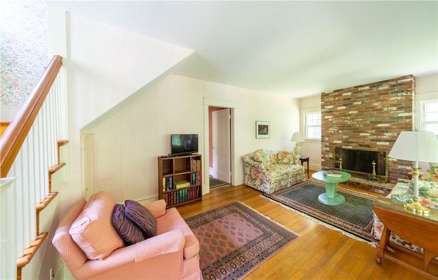 living room featuring brick wall, a fireplace, and hardwood / wood-style floors