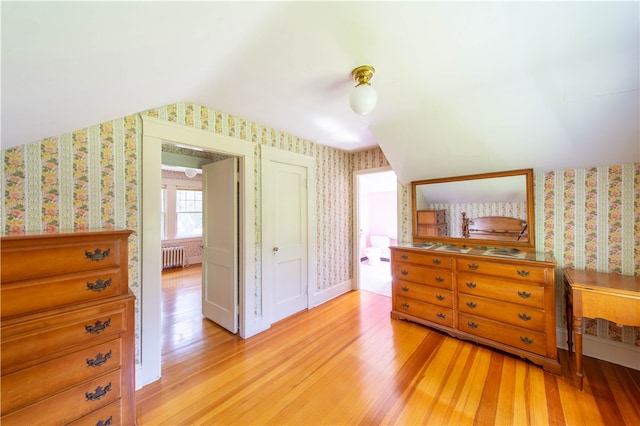 bedroom featuring radiator heating unit, light wood-type flooring, and vaulted ceiling