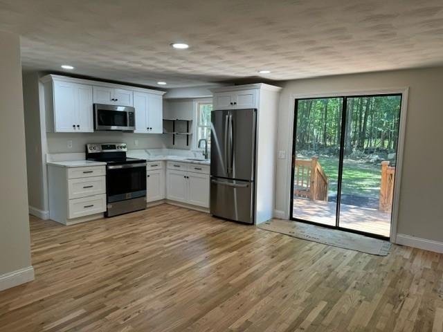 kitchen featuring white cabinetry, stainless steel appliances, light hardwood / wood-style floors, and a healthy amount of sunlight