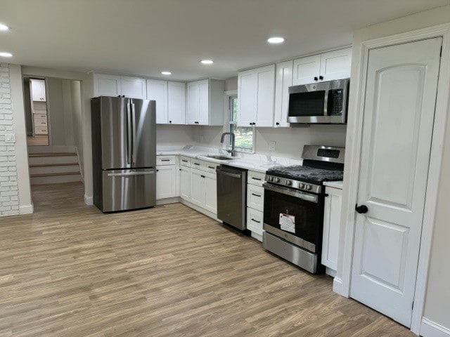 kitchen featuring sink, light hardwood / wood-style flooring, stainless steel appliances, and white cabinets